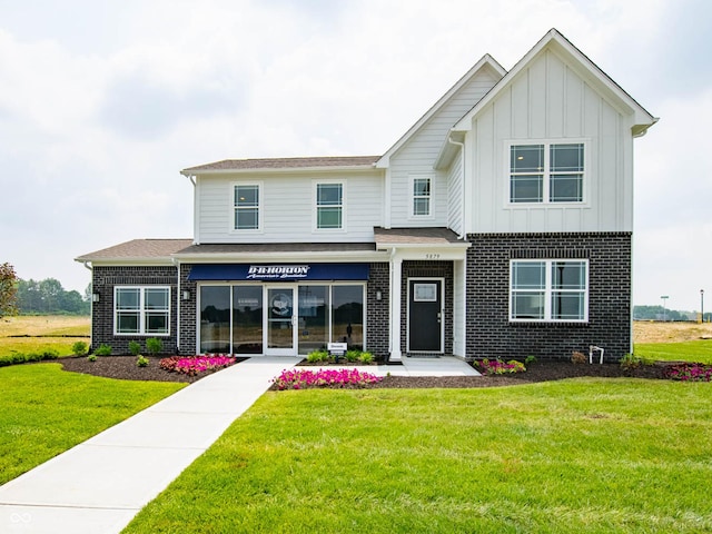 view of front of home featuring board and batten siding, a front yard, and brick siding