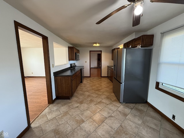 kitchen featuring appliances with stainless steel finishes, dark countertops, a healthy amount of sunlight, and baseboards