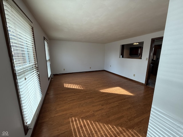 empty room with dark wood-style floors and baseboards