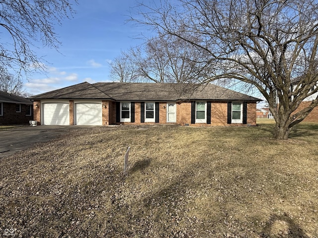 ranch-style home with aphalt driveway, a front yard, brick siding, and a garage