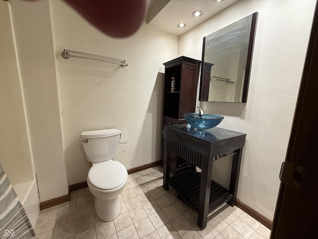 full bathroom with a tub, tile patterned flooring, baseboards, and toilet