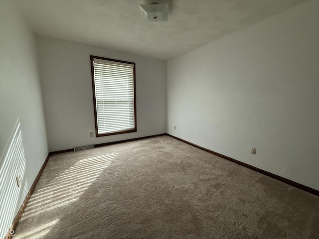 spare room with light carpet, visible vents, and baseboards