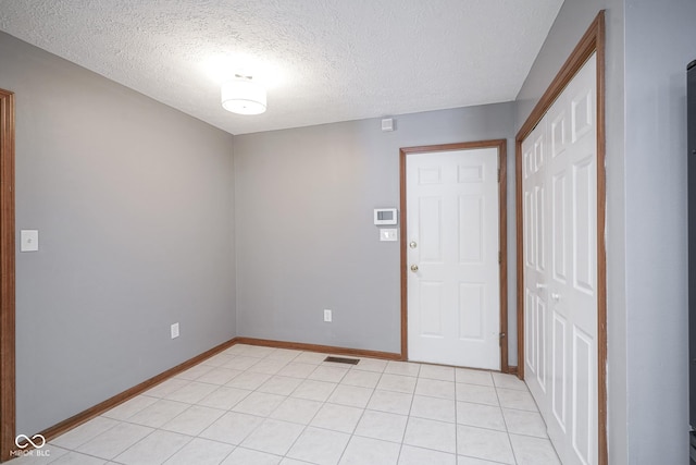 entrance foyer with light tile patterned floors, baseboards, visible vents, and a textured ceiling