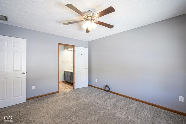 unfurnished bedroom with visible vents, light colored carpet, connected bathroom, a textured ceiling, and baseboards