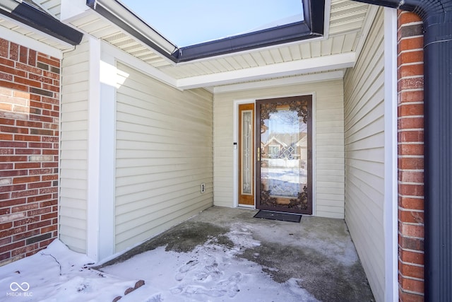 entrance to property featuring a garage and brick siding