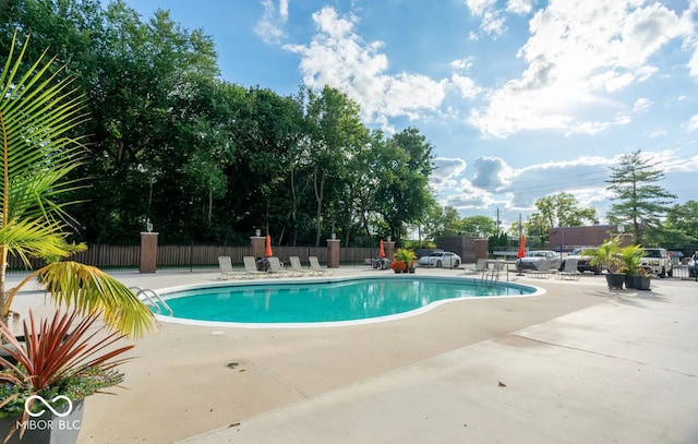 community pool with a patio area and fence