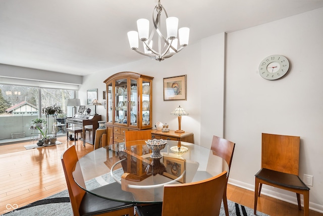 dining space featuring light wood-style floors, baseboards, and an inviting chandelier