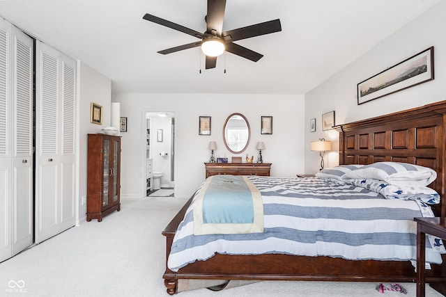 bedroom featuring light carpet, ensuite bath, and a ceiling fan