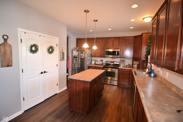 kitchen with appliances with stainless steel finishes, a center island, hanging light fixtures, light countertops, and a sink