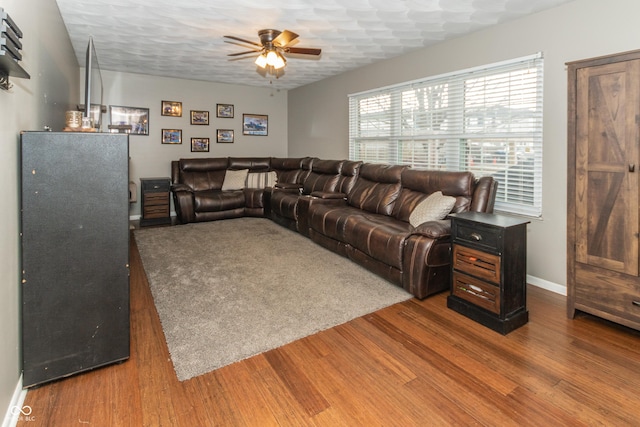 living room with ceiling fan, a textured ceiling, wood finished floors, and baseboards