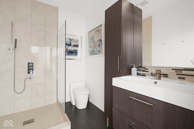 bathroom featuring tasteful backsplash, toilet, wood finished floors, vanity, and a shower stall