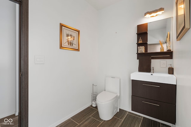 bathroom featuring baseboards, vanity, and toilet