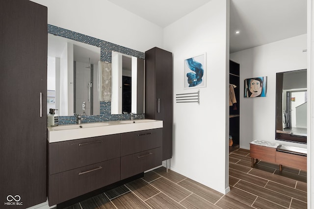 bathroom featuring baseboards, double vanity, a sink, and wood tiled floor