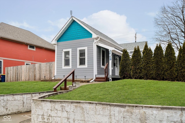 exterior space featuring roof with shingles, a yard, and fence