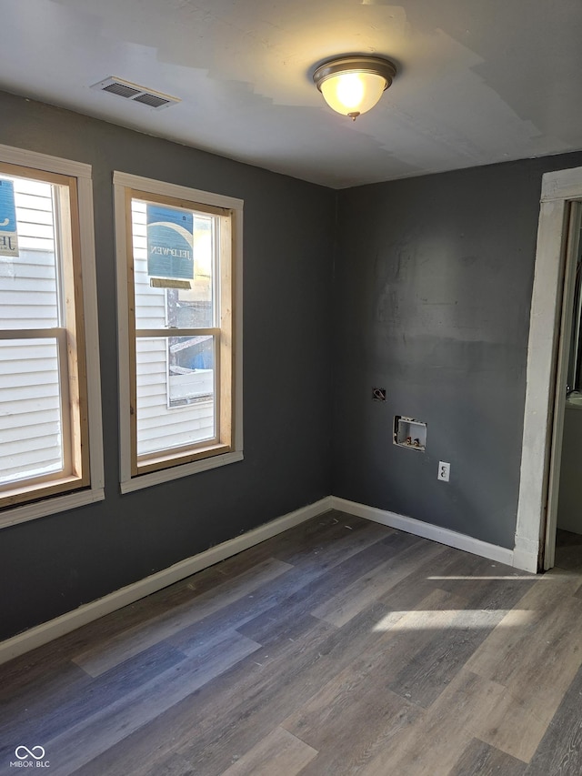 empty room with dark wood-type flooring, visible vents, and baseboards