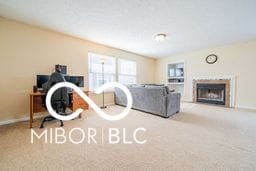 living area featuring a fireplace, baseboards, and light colored carpet