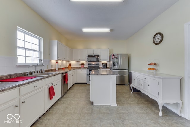 387 Legacy Blvd, Greenwood, IN 46143 - kitchen with appliances with stainless steel finishes, a sink, a kitchen island, white cabinets, and light tile patterned floors