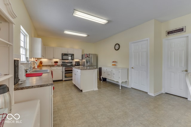 387 Legacy Blvd, Greenwood, IN 46143 - kitchen featuring stainless steel appliances, a sink, dark countertops, a kitchen island, and white cabinetry