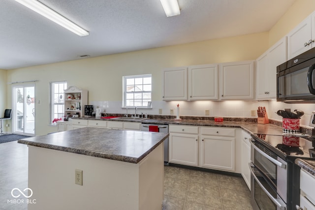 387 Legacy Blvd, Greenwood, IN 46143 - kitchen featuring stainless steel appliances, a sink, dark countertops, white cabinetry, and a kitchen island