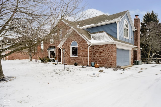 traditional-style house with brick siding, a chimney, a shingled roof, central AC unit, and a garage