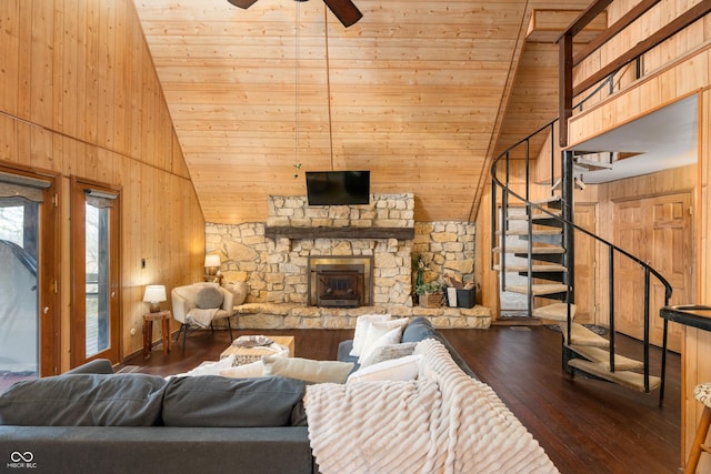 living area with high vaulted ceiling, dark wood-type flooring, wood walls, a ceiling fan, and stairway