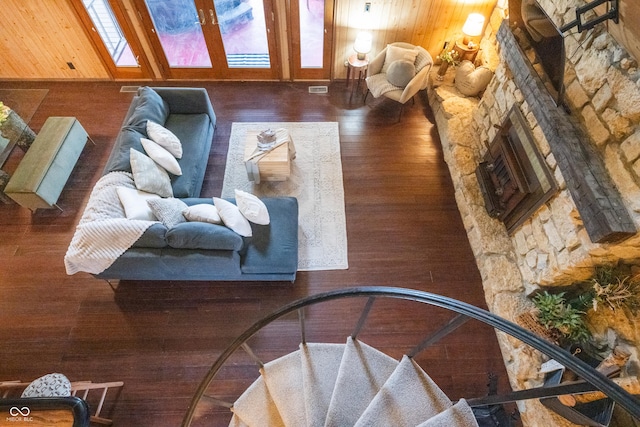 living area featuring wood walls, a fireplace, visible vents, and wood finished floors