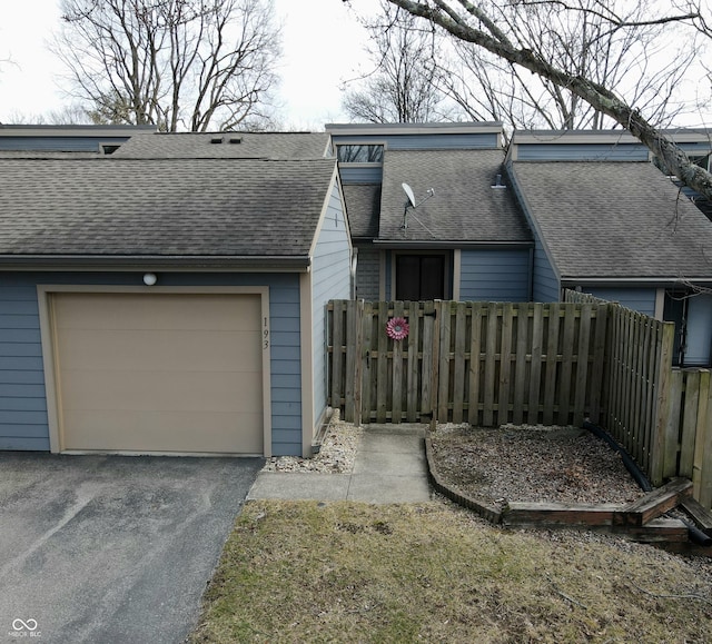 view of front of property featuring a garage, roof with shingles, fence, and aphalt driveway