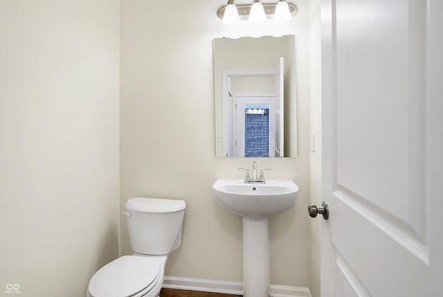 half bath featuring toilet and baseboards