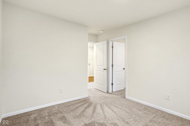 unfurnished room featuring baseboards and light carpet