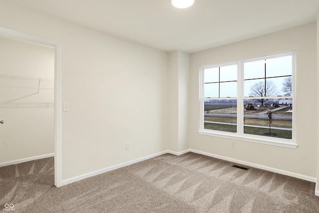 unfurnished bedroom featuring a spacious closet, visible vents, baseboards, and carpet floors