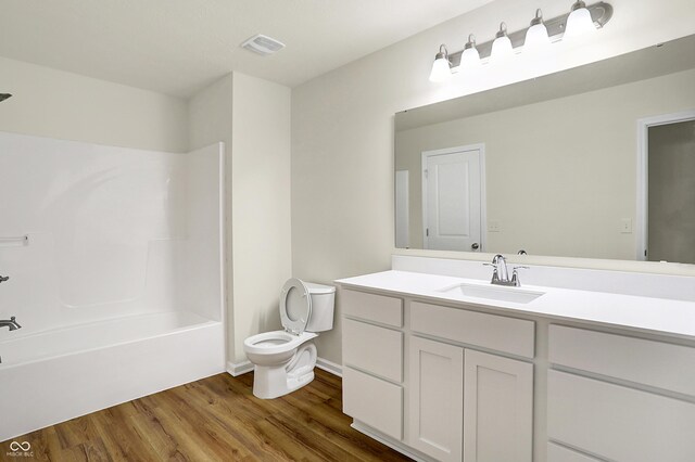 full bathroom featuring visible vents, toilet, wood finished floors, vanity, and  shower combination