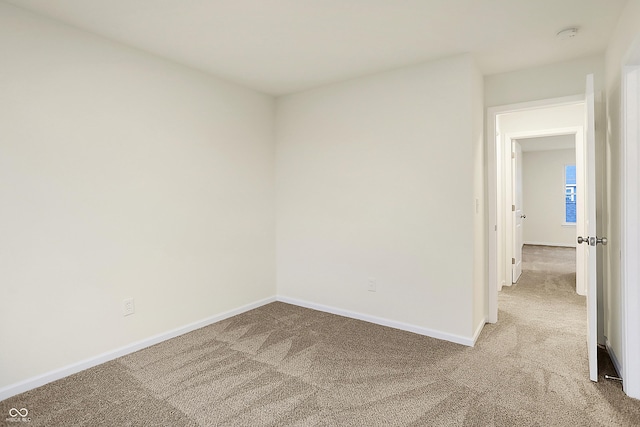 unfurnished room with light carpet and baseboards