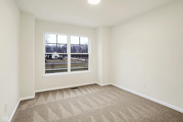 empty room featuring visible vents, baseboards, and carpet