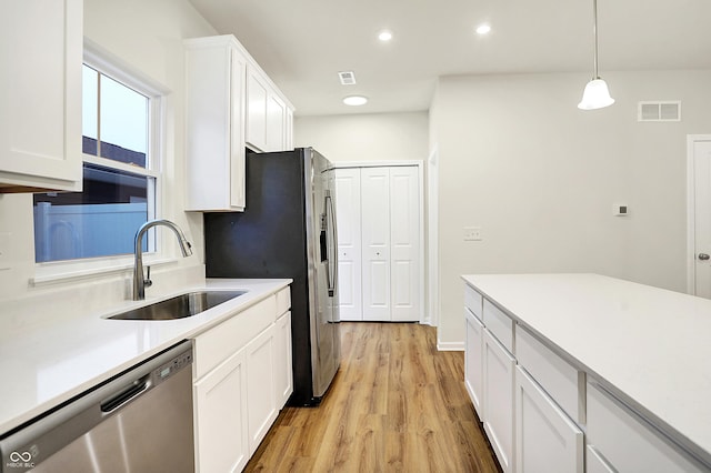 kitchen with visible vents, a sink, stainless steel dishwasher, white cabinetry, and light wood finished floors