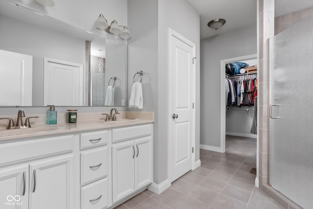 bathroom featuring double vanity, a stall shower, a walk in closet, and a sink