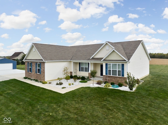 view of front of house featuring brick siding, a front yard, and a shingled roof