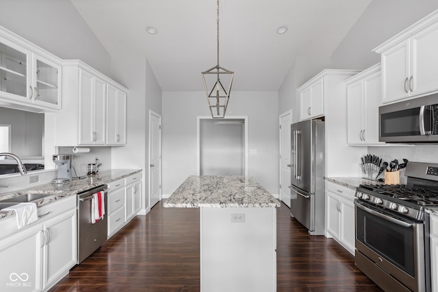 kitchen with white cabinetry, a kitchen island, glass insert cabinets, and stainless steel appliances