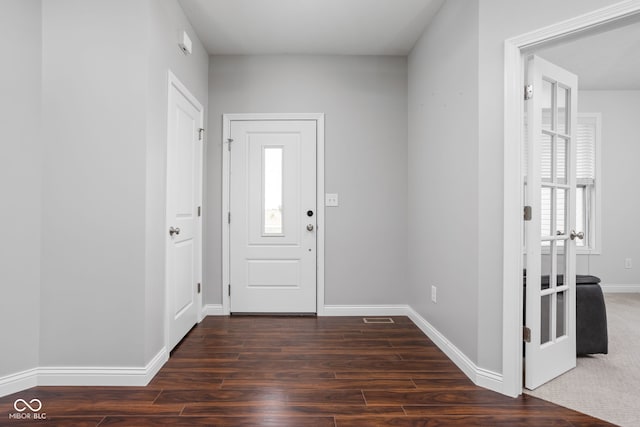 foyer entrance with dark wood-type flooring, visible vents, and baseboards