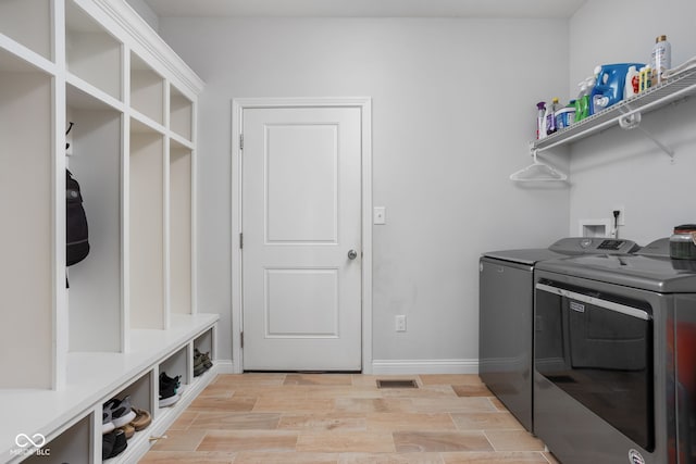 washroom with laundry area, washing machine and dryer, baseboards, and wood finish floors