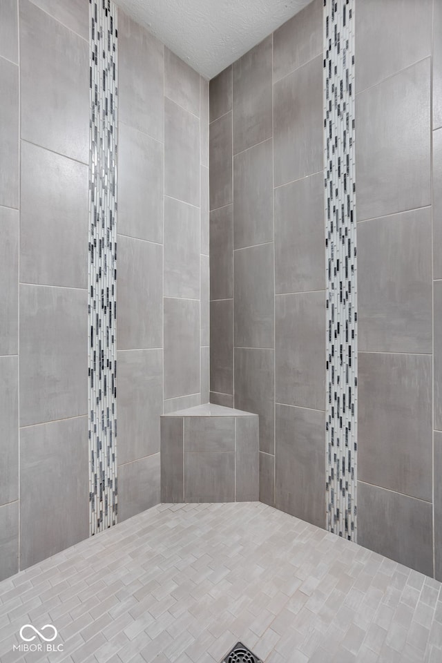 full bathroom with a textured ceiling and tiled shower