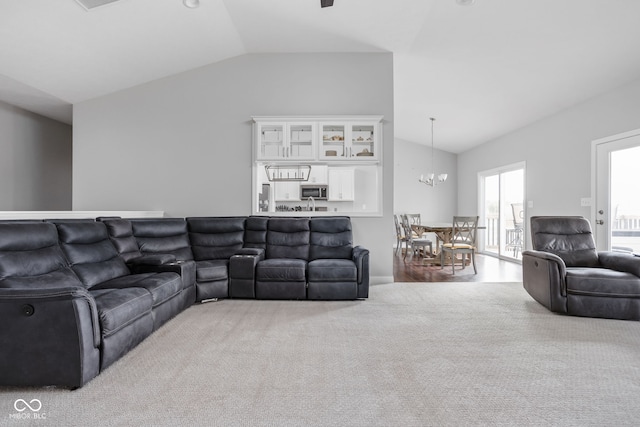 living area featuring lofted ceiling, carpet floors, and a notable chandelier