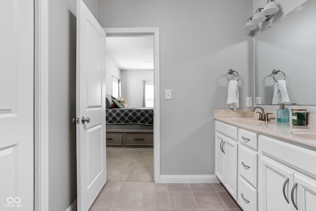 bathroom featuring double vanity, connected bathroom, a sink, baseboards, and tile patterned floors