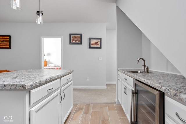 kitchen featuring hanging light fixtures, wine cooler, light countertops, and white cabinetry