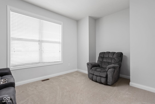 sitting room with baseboards, visible vents, and light colored carpet