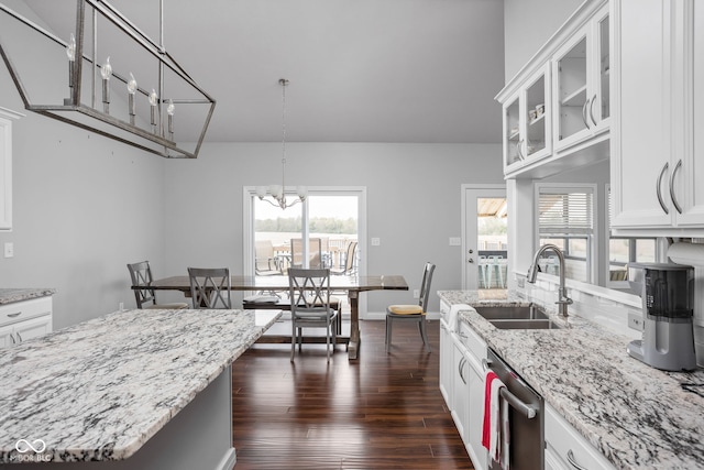 kitchen featuring glass insert cabinets, stainless steel dishwasher, white cabinetry, pendant lighting, and a sink