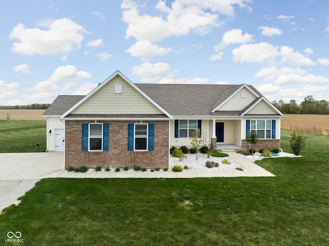 view of front of house with a front yard, covered porch, brick siding, and driveway