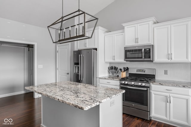 kitchen featuring light stone counters, stainless steel appliances, white cabinets, a center island, and dark wood-style floors