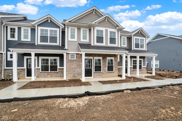 view of front facade featuring board and batten siding, covered porch, and stone siding