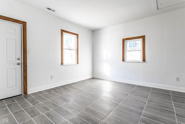 unfurnished room featuring dark tile patterned floors, visible vents, and baseboards
