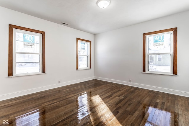 unfurnished room featuring baseboards, dark wood-style flooring, and plenty of natural light